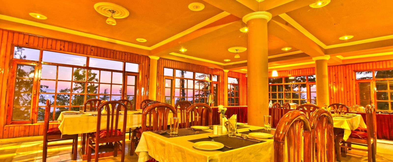 Restaurant with chairs, tables, and cutlery set up at DLS Hillcrest Resort, Shimla.
